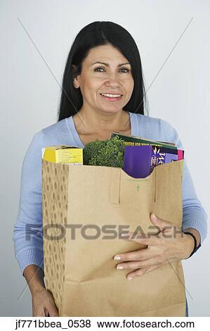 Stock Photo - Hispanic woman carrying grocery bag. Fotosearch