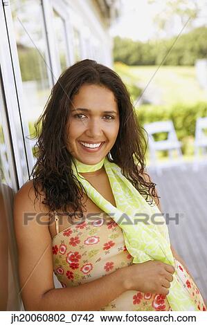 Stock Image - Hispanic woman leaning against glass door. Fotosearch