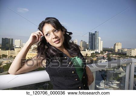 Stock Photograph - Hispanic woman leaning on balcony railing. Fotosearch