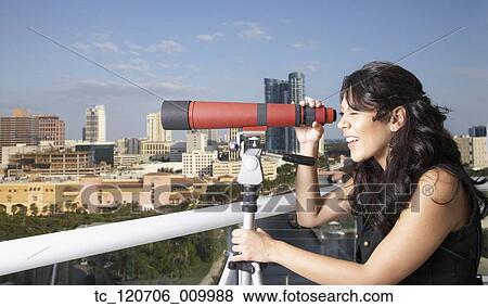 Hispanic woman looking through telescope on balcony View Large Photo Image Stock Photo - Hispanic woman looking through telescope on balcony. Fotosearch
