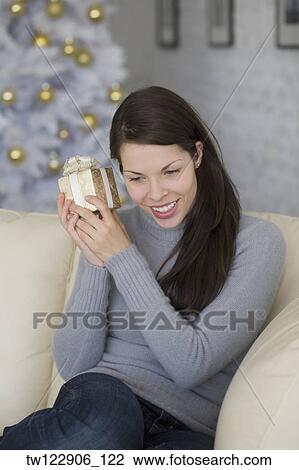 Hispanic woman shaking Christmas gift View Large Photo Image Stock Image - Hispanic woman shaking Christmas gift. Fotosearch