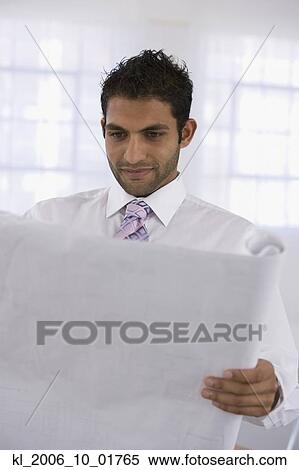 Stock Photography - Indian businessman looking at blueprints. Fotosearch