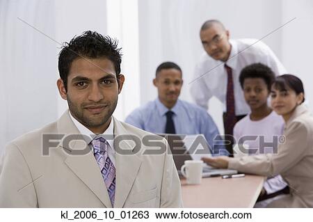 Stock Image - Indian businessman with co-workers in background. Fotosearch