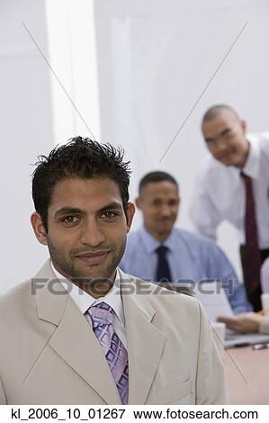 Indian businessman with co-workers in background View Large Photo Image Stock Photo - Indian businessman with co-workers in background. Fotosearch
