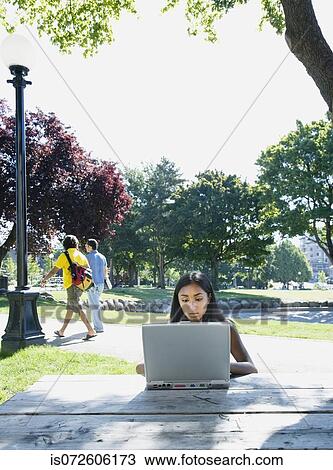 Indian woman typing on laptop outdoors View Large Photo Image Stock Image - Indian woman typing on laptop outdoors. Fotosearch