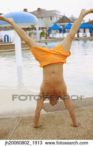 Man performing handstand next to swimming pool View Large Photo Image Stock Image - Man performing handstand next to swimming pool. Fotosearch