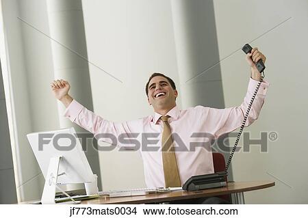 Middle Eastern businessman cheering at desk View Large Photo Image Picture - Middle Eastern businessman cheering at desk. Fotosearch
