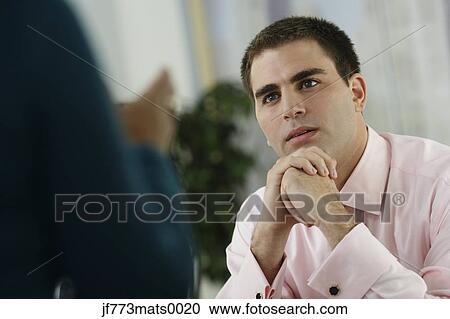 Stock Image - Middle Eastern businessman listening to coworker. Fotosearch