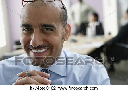 Stock Image - Middle Eastern businessman with hands clasped. Fotosearch