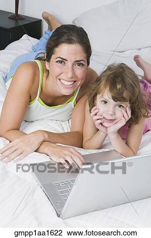 Mother and daughter with laptop on bed View Large Photo Image Stock Image - Mother and daughter with laptop on bed. Fotosearch