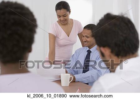 Stock Image - Multi-ethnic businesspeople looking at paperwork. Fotosearch