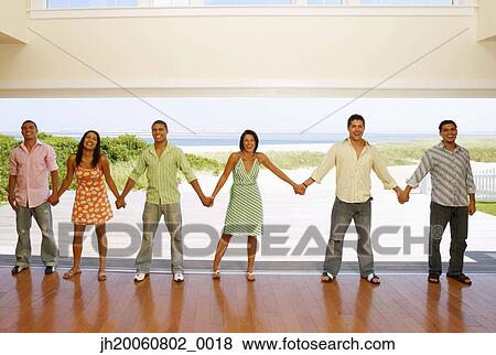 Multi-ethnic friends holding hands at beach resort View Large Photo Image Stock Photo - Multi-ethnic friends holding hands at beach resort. Fotosearch