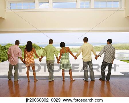 Multi-ethnic friends holding hands at beach resort View Large Photo Image Stock Photo - Multi-ethnic friends holding hands at beach resort. Fotosearch