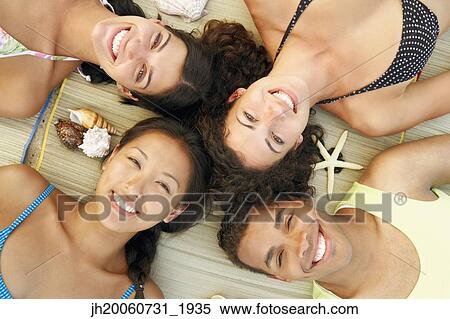 Multi-ethnic friends laying on beach View Large Photo Image Stock Photography - Multi-ethnic friends laying on beach. Fotosearch