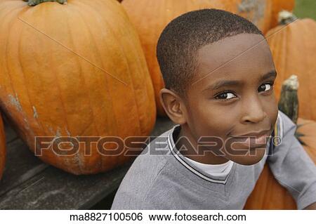 Portrait of African boy next to pumpkins View Large Photo Image Stock Photograph - Portrait of African boy next to pumpkins. Fotosearch