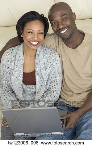 Stock Photograph - Portrait of African couple with laptop. Fotosearch