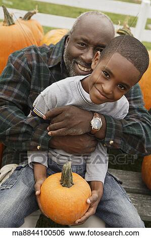 Portrait of African father and son holding pumpkin View Large Photo Image Stock Photograph - Portrait of African father and son holding pumpkin . Fotosearch