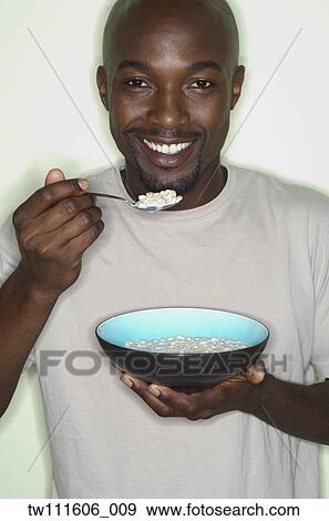 Stock Photo - Portrait of African man eating cereal. Fotosearch