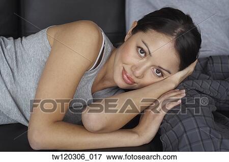 Stock Photo - Portrait of Hispanic woman laying on boyfriend’s leg. Fotosearch