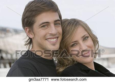 Stock Image - Portrait of young couple hugging. Fotosearch
