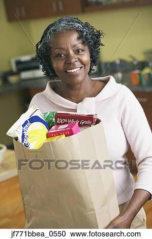 Stock Image - Senior African woman carrying grocery bag. Fotosearch