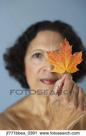 Senior African woman holding autumn leaf over eye View Large Photo Image Stock Image - Senior African woman holding autumn leaf over eye. Fotosearch