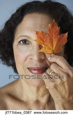Senior African woman holding autumn leaf over eye View Large Photo Image Stock Photo - Senior African woman holding autumn leaf over eye. Fotosearch