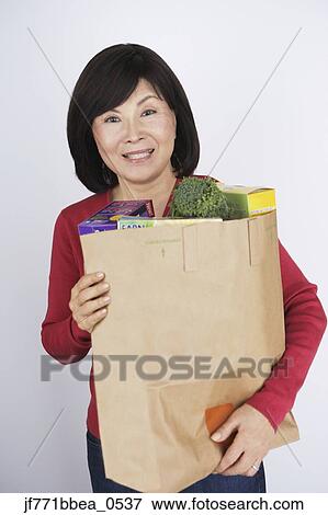 Stock Photo - Senior Asian woman carrying grocery bag. Fotosearch