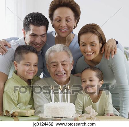 Stock Image - Senior Hispanic man celebrating birthday with family. Fotosearch