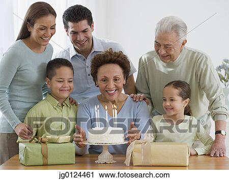 Stock Image - Senior Hispanic woman celebrating birthday with family. Fotosearch