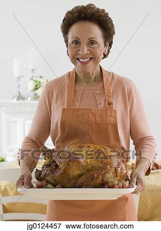 Senior Hispanic woman holding roast turkey View Large Photo Image Stock Photo - Senior Hispanic woman holding roast turkey. Fotosearch