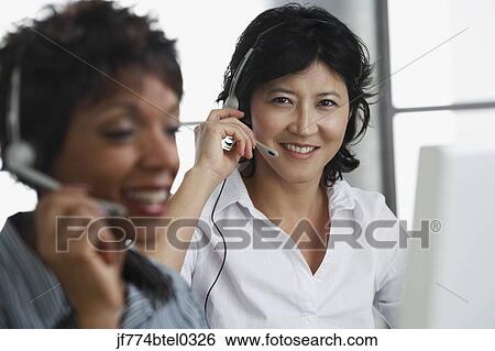 Two businesswomen wearing headsets View Large Photo Image Stock Photograph - Two businesswomen wearing headsets. Fotosearch