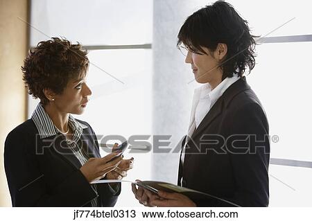 Two multi-ethnic businesswomen talking View Large Photo Image Stock Image - Two multi-ethnic businesswomen talking. Fotosearch