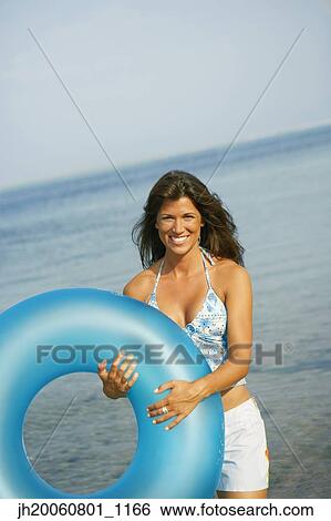 Woman holding inner tube at beach View Large Photo Image Stock Photograph - Woman holding inner tube at beach. Fotosearch