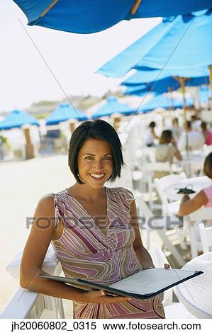 Stock Photography - Woman holding menu at beach restaurant. Fotosearch