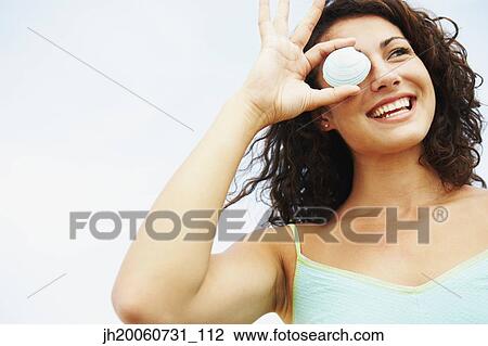 Woman holding seashell over eye View Large Photo Image Stock Image - Woman holding seashell over eye. Fotosearch