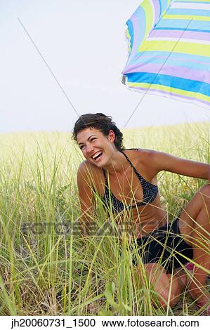 Woman laughing under beach umbrella View Large Photo Image Stock Image - Woman laughing under beach umbrella. Fotosearch