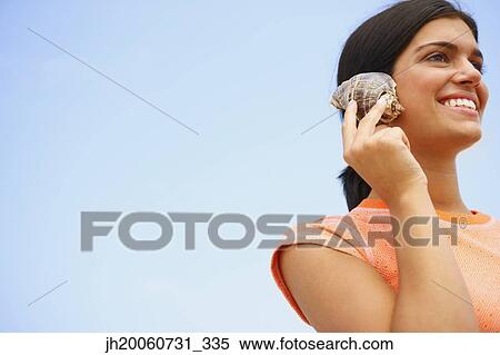 Woman listening to seashell View Large Photo Image Stock Photography - Woman listening to seashell. Fotosearch