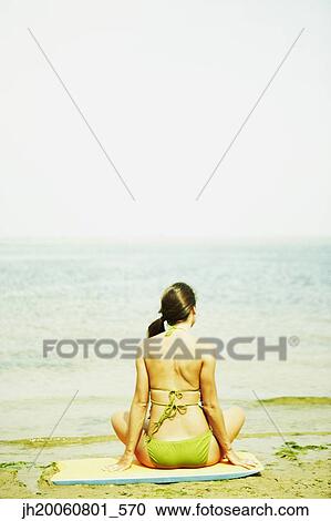 Stock Image - Woman sitting on beach. Fotosearch