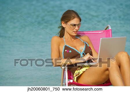Woman typing on laptop at beach View Large Photo Image Stock Image - Woman typing on laptop at beach. Fotosearch