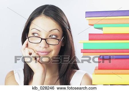 Stock Photograph - Woman wearing eyeglasses next to stack of books. Fotosearch