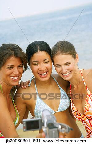 Stock Image - Women video recording themselves at beach. Fotosearch