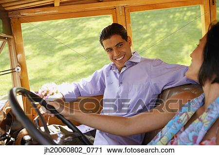 Stock Image - Young couple driving old fashioned car. Fotosearch