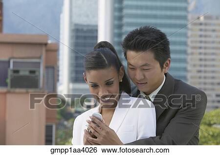 Stock Photograph - Young couple looking at cell phone. Fotosearch