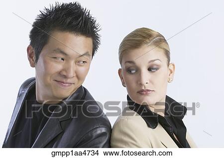 Picture - Young couple looking over shoulder at each other. Fotosearch
