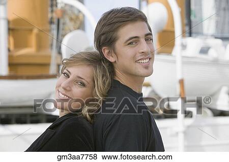 Young couple standing back to back View Large Photo Image Stock Photo - Young couple standing back to back. Fotosearch
