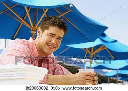 Young man holding drink outdoors View Large Photo Image Stock Photography - Young man holding drink outdoors. Fotosearch