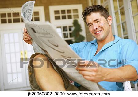 Stock Image - Young man reading newspaper. Fotosearch