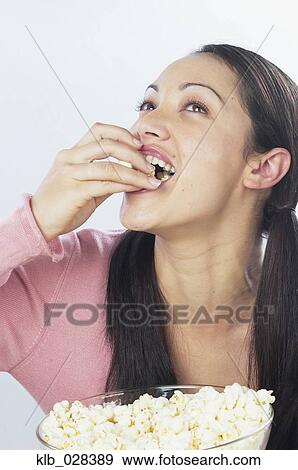 Young woman eating popcorn View Large Photo Image Stock Photo - Young woman eating popcorn. Fotosearch
