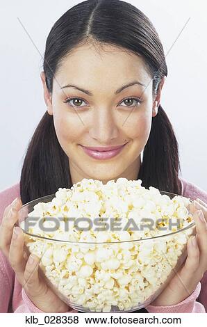 Young woman holding bowl of popcorn View Large Photo Image Stock Photo - Young woman holding bowl of popcorn. Fotosearch